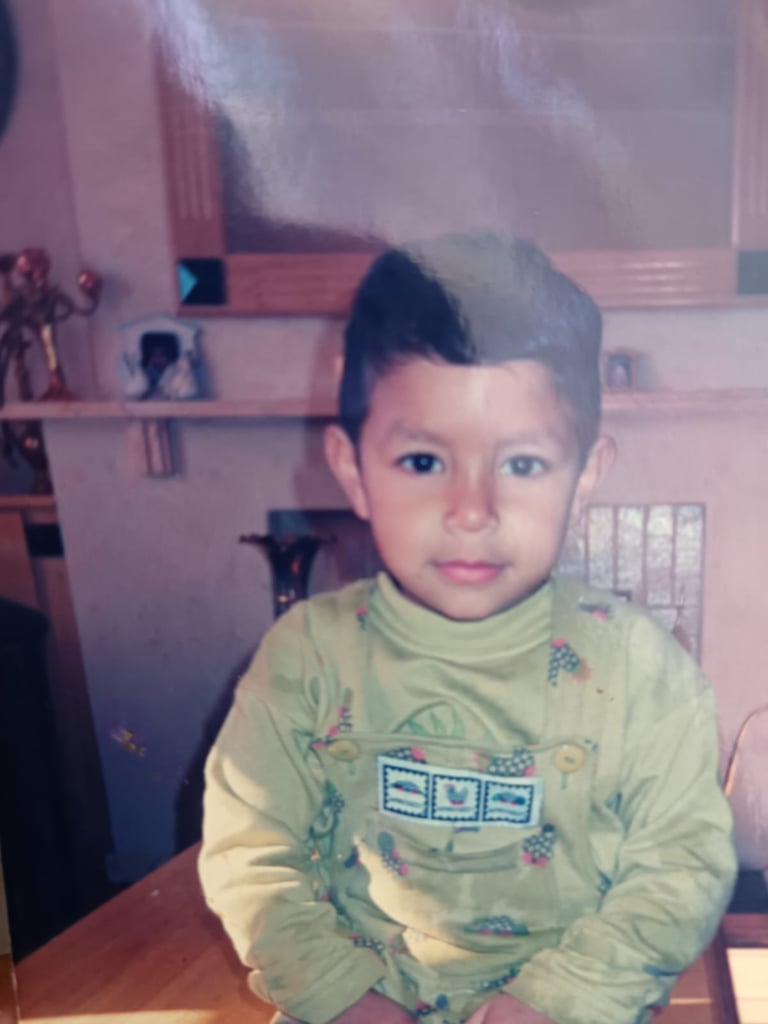 Young child sitting at a desk wearing a light green long-sleeved shirt with decorative patterns